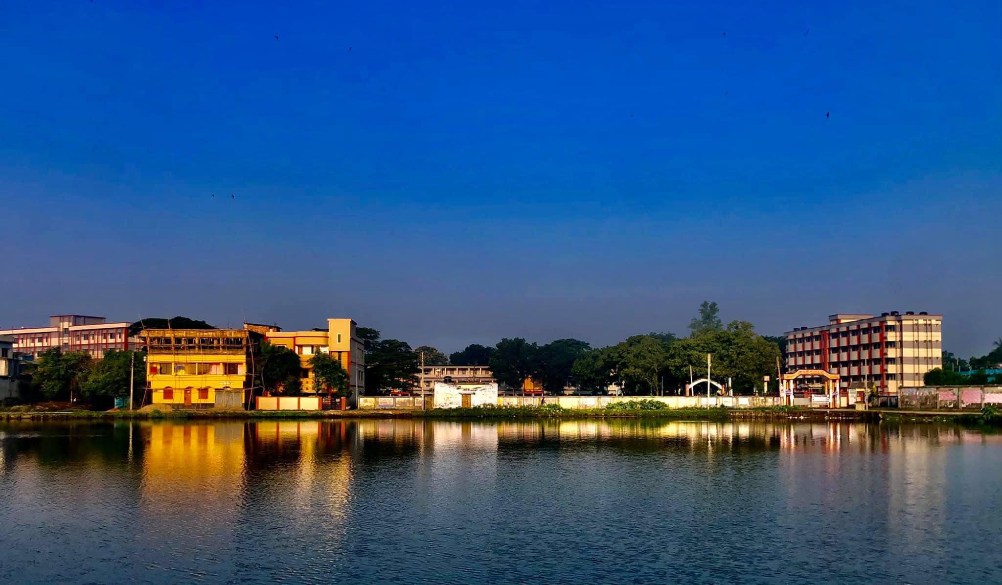 Urban buildings reflecting in a calm body of water during the day.
