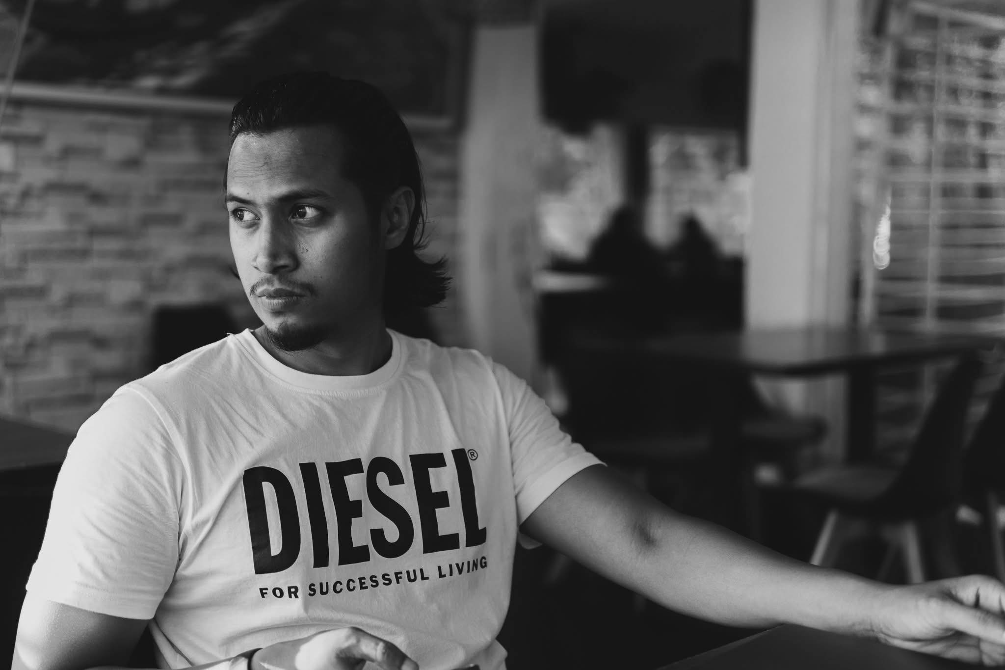 Black and white portrait of a man looking off-camera in a cafe setting.